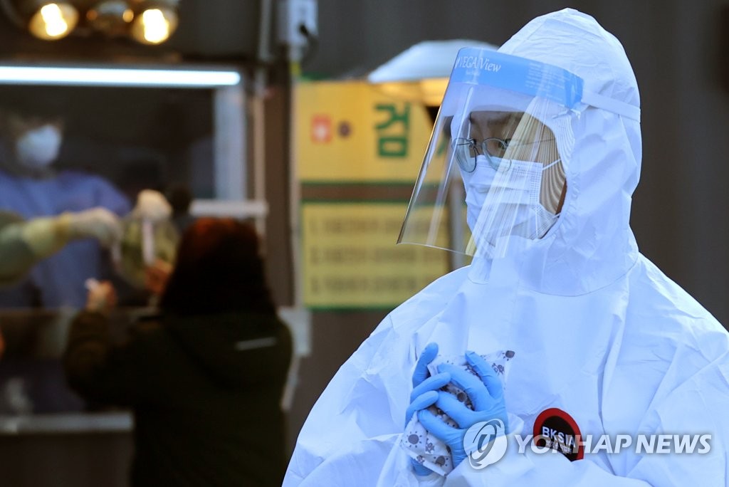 A medical staffer holds hand warmers at an outdoor COVID-19 testing station in Seoul on Dec. 21, 2020, amid a cold wave. (Yonhap)