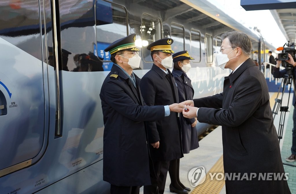President Moon Jae-in (R) hands over the master key of the KTX-Eum high-speech train to its engineer, Jeon Seong-soo, during a ceremony held at the Wonju Station in Gangwon Province on Jan. 4, 2021. (Yonhap)