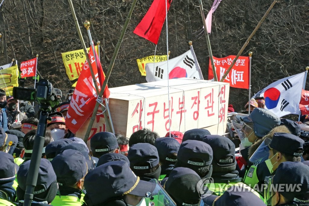 A group of residents shoulders a wooden bier to carry a simulated coffin for the defense minister during a rally in front of an Apache helicopter firing range in Pohang, North Gyeongsang Province, southeastern South Korea, on Feb. 4, 2021, calling for the closure of the live-fire firing site of the U.S. Forces Korea. (Yonhap)