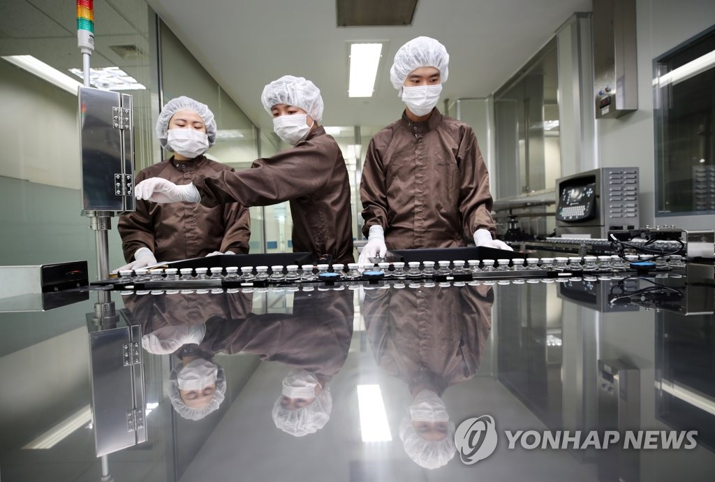 Workers look at bottles of pharmaceutical giant Celltrion Inc.'s COVID-19 antibody treatment, CT-P59, on its production line at a plant of the South Korean company in Incheon, west of Seoul, on Feb. 9, 2021. (Yonhap)