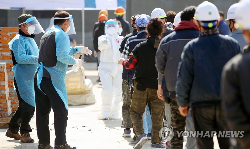 Des gens font la queue avant de se soumettre à un test de dépistage du nouveau coronavirus (Covid-19) dans une station de test provisoire installée sur un chantier de construction à Gyeongsan, à 331 kilomètres au sud de Séoul, le 11 mars 2021.