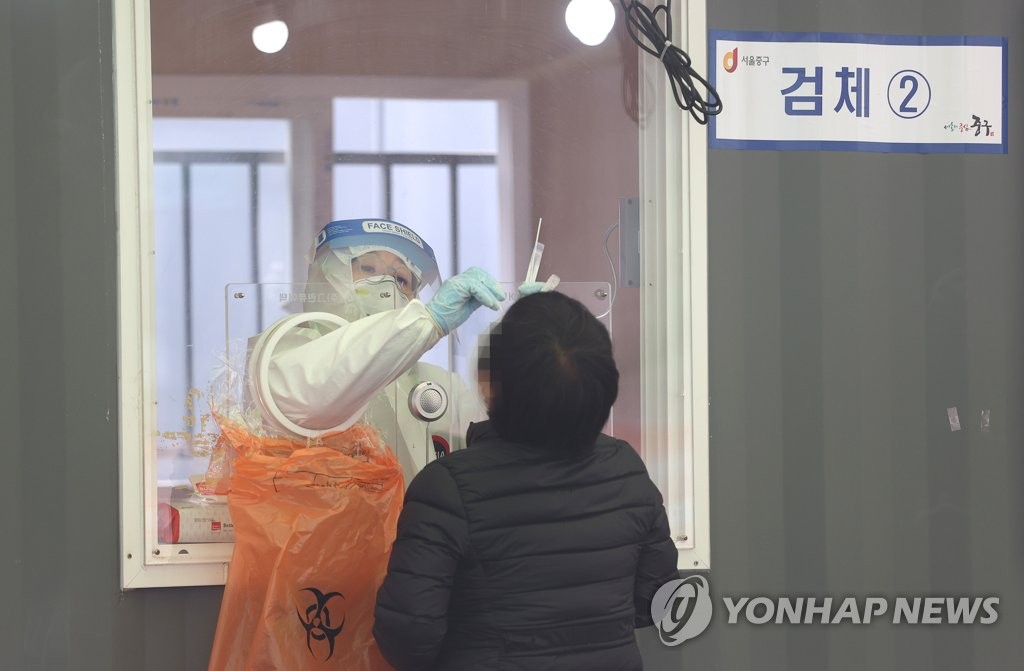 A health worker collects a sample from a citizen for a COVID-19 test at a makeshift virus testing clinic in Seoul on March 13, 2021. (Yonhap)