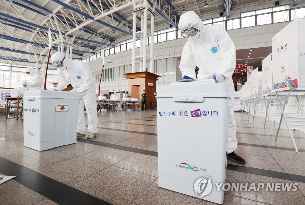 Medical workers disinfect ballot boxes amid the coronavirus pandemic at a polling station installed inside Seoul Station on April 1, 2021, one day ahead of two-day early voting for the April 7 Seoul mayoral by-election. (Yonhap)