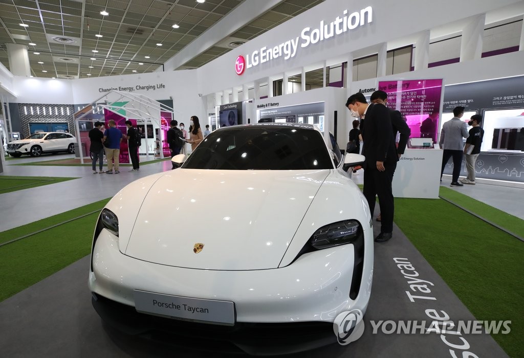 A visitor to LG Energy Solution Ltd.'s exhibition booth at InterBattery 2021 in Seoul looks at a Porsche Taycan electric vehicle equipped with LG's battery on June 9, 2021. (Yonhap)