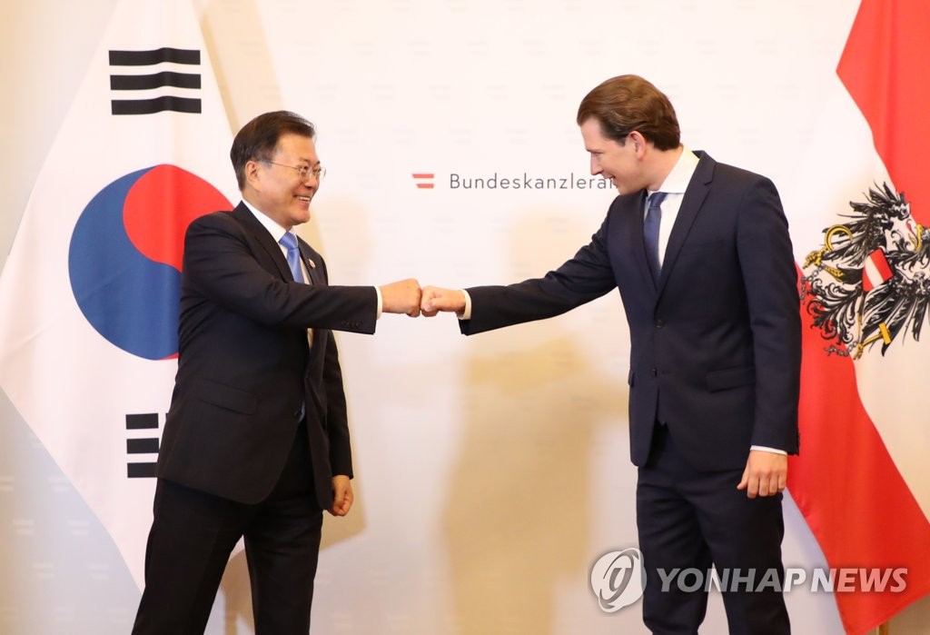 South Korean President Moon Jae-in (L) bumps fists with Austrian Chancellor Sebastian Kurz at the chancellor's office in Vienna on June 14, 2021. (Yonhap)