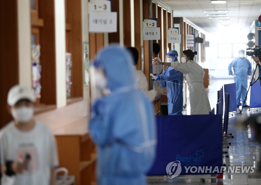 Quarantine officials work at temporary testing stations set up at an elementary school in Daejeon on July 22, 2021. (Yonhap) 