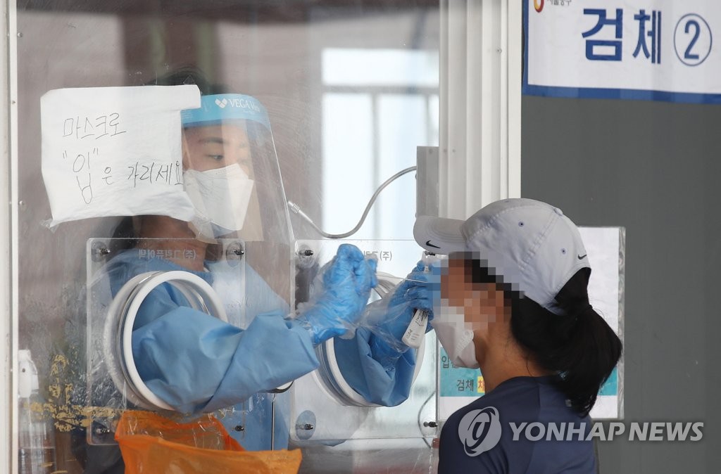A health worker tests a woman for COVID-19 at a walk-in center set up at the plaza in front of Seoul Station in central Seoul on Aug. 1, 2021. (Yonhap)