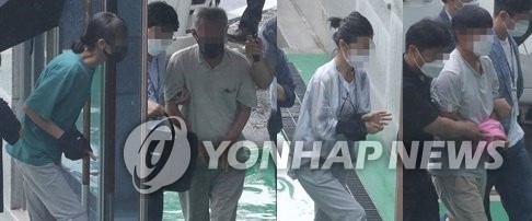 Quatre militants sud-coréens arrivent à la Cour du district de Cheongju, à environ 140 kilomètres au sud de Séoul, pour assister à une audience de mandat d'arrêt, le 2 août 2021. Ils sont suspectés d'avoir reçu des ordres de la Corée du Nord pour organiser des manifestations anti-armes.