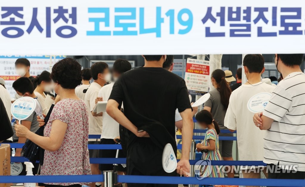 People use hand fans to cool off amid the sweltering heat as they wait to get tested for COVID-19 at a screening center in Sejong, 120 kilometers south of Seoul, on Aug. 5, 2021. (Yonhap)