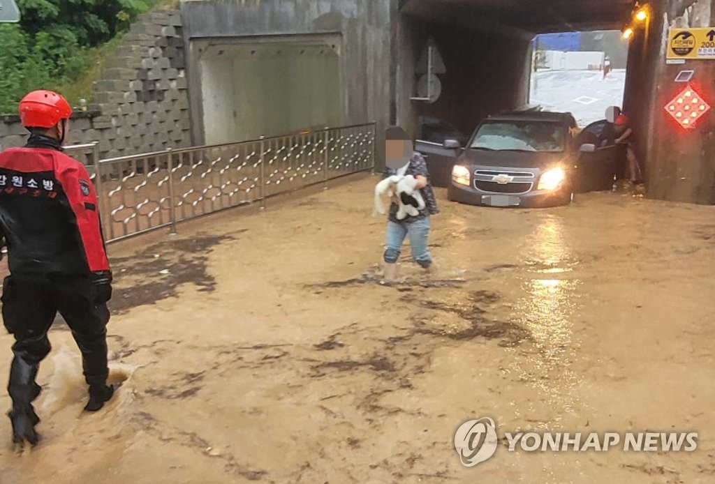 This photo, provided by Gangwon Fire Headquarters, shows firefighters rescuing passengers from a vehicle trapped in a flooded underpass in Goseong, Gangwon Province, on Aug. 8, 2021. (PHOTO NOT FOR SALE) (Yonhap)