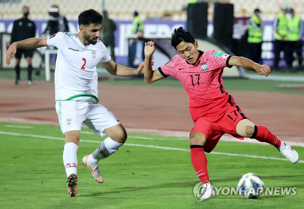 Na Sang-ho of South Korea (R) tries to dribble past Sadegh Moharrami of Iran during the teams' Group A match in the final Asian qualifying round for the 2022 FIFA World Cup at Azadi Stadium in Tehran on Oct. 12, 2021. (Yonhap)
