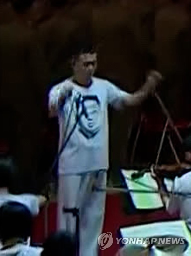 This image, captured from North Korea's official Korean Central TV Broadcasting Station, shows an orchestra conductor wearing a T-shirt printed with the portrait of the North's leader Kim Jong-un during a defense expo in Pyongyang on Oct. 11, 2021. (For Use Only in the Republic of Korea. No Redistribution) (Yonhap) 