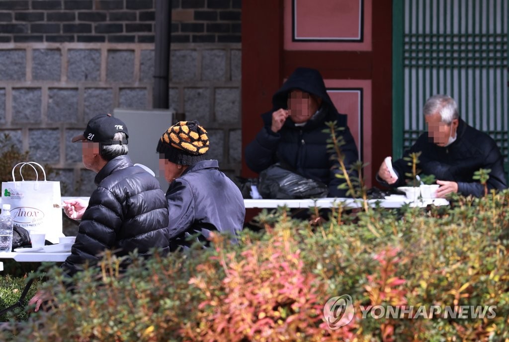 This file photo taken Nov. 10, 2021, shows older adults eating free meals at a park in central Seoul. (Yonhap)