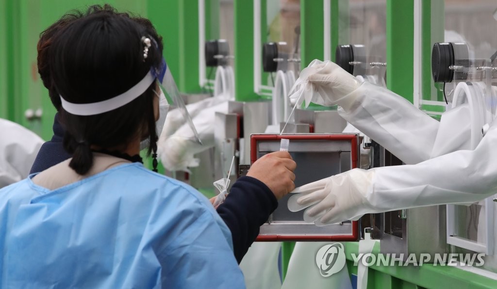 Health workers conduct COVID-19 tests on citizens at a makeshift testing center in southern Seoul amid the latest spike in COVID-19 cases. (Yonhap)