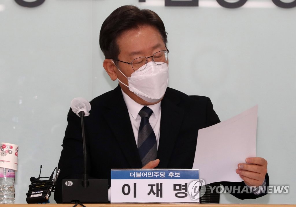 Lee Jae-myung, the presidential candidate of the ruling Democratic Party, looks at a report during his meeting with small business owners and self-employed people at the Korea Federation of SMEs in Seoul on Dec. 20, 2021. (Pool photo) (Yonhap)