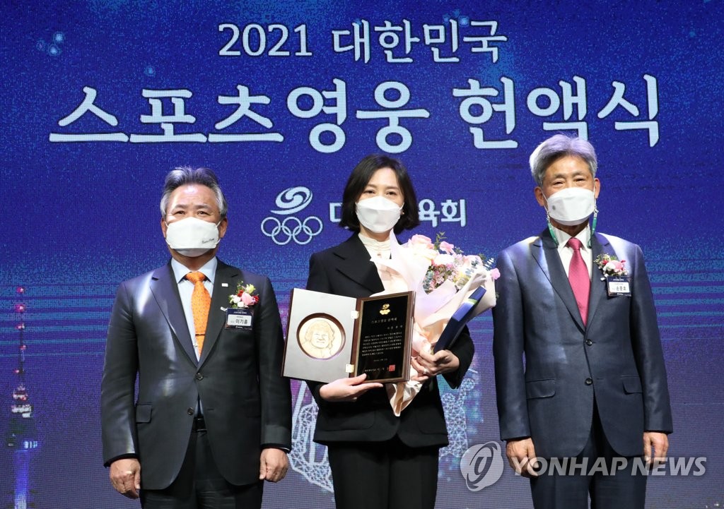 Bang Young-eun (C), the wife of late South Korean mountaineer Kim Hong-bin, poses with a plaque posthumously awarded to Kim as the 2021 South Korean Sports Hero during the Sports Hall of Fame induction ceremony at Olympic Park in Seoul on Dec. 22, 2021. Bang is flanked by Korean Sport and Olympic Committee President Lee Kee-heung (L) and the Korea Alpine Federation President Son Joong-ho. (Yonhap)