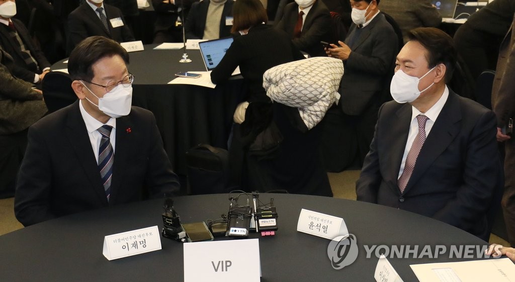 Lee Jae-myung (L), the presidential nominee of the ruling Democratic Party, speaks with Yoon Suk-yeol, the nominee of the main opposition People Power Party, at an awards ceremony in Seoul on Dec. 27, 2021. (Pool photo) (Yonhap)