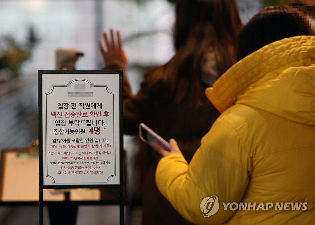 A notice is set up in front of a restaurant in Seoul on Jan. 3, 2022, to inform people that vaccine passes are effective only for six months starting the same day, requiring people to get booster shots to enter multiuse facilities, including cafes, gyms and cultural facilities, if they received their vaccines over six months ago. (Yonhap)