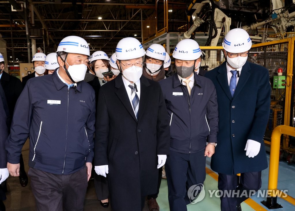 Lee Jae-myung (2nd from L), the presidential candidate of the ruling Democratic Party, takes a tour of a plant of the Kia Corp. carmaker in Gwangmyeong, near Seoul, on Jan. 4, 2022. (Pool photo) (Yonhap)