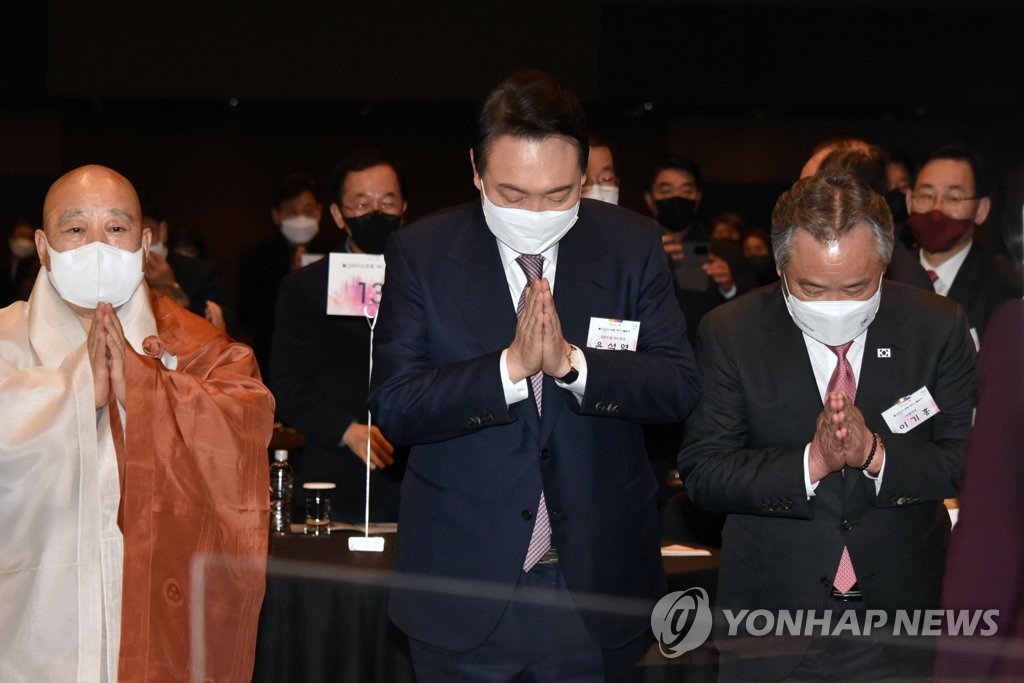 Yoon Suk-yeol (C), the presidential nominee of the main opposition People Power Party, presses his hands together at a Buddhist leaders forum at a Seoul hotel on Jan. 17, 2022. (Pool photo) (Yonhap)