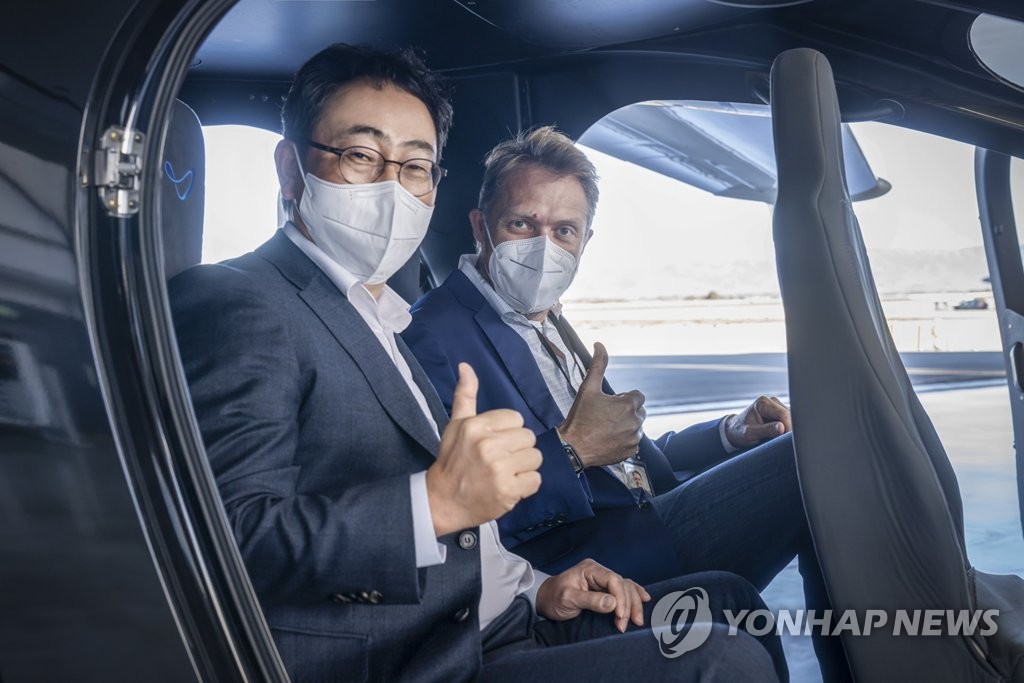 This photo, provided by SK Telecom Co. (SKT), shows SKT CEO Ryu Young-sang (L) posing with JoeBen Bevirt, head of Joby Aviation, in a urban air mobility (UAM) vehicle during a visit to the American UAM manufacturer in California last month. SKT, South Korea's biggest mobile carrier, said on Feb. 7, 2022, that the two companies have signed a UAM business accord. (PHOT NOT FOR SALE) (Yonhap)
