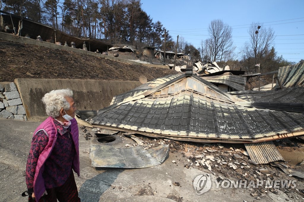 A resident in Uljin looks at her house on March 6, 2022, after it burned down in a fire. (Yonhap)