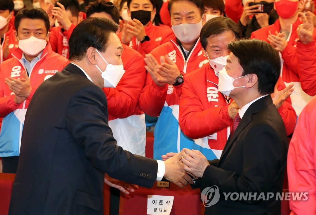 This photo taken on March 10, 2022, shows President-elect Yoon Suk-yeol (L) shaking hands with People's Party chief Ahn Cheol-soo at the National Assembly in Seoul. (Yonhap)