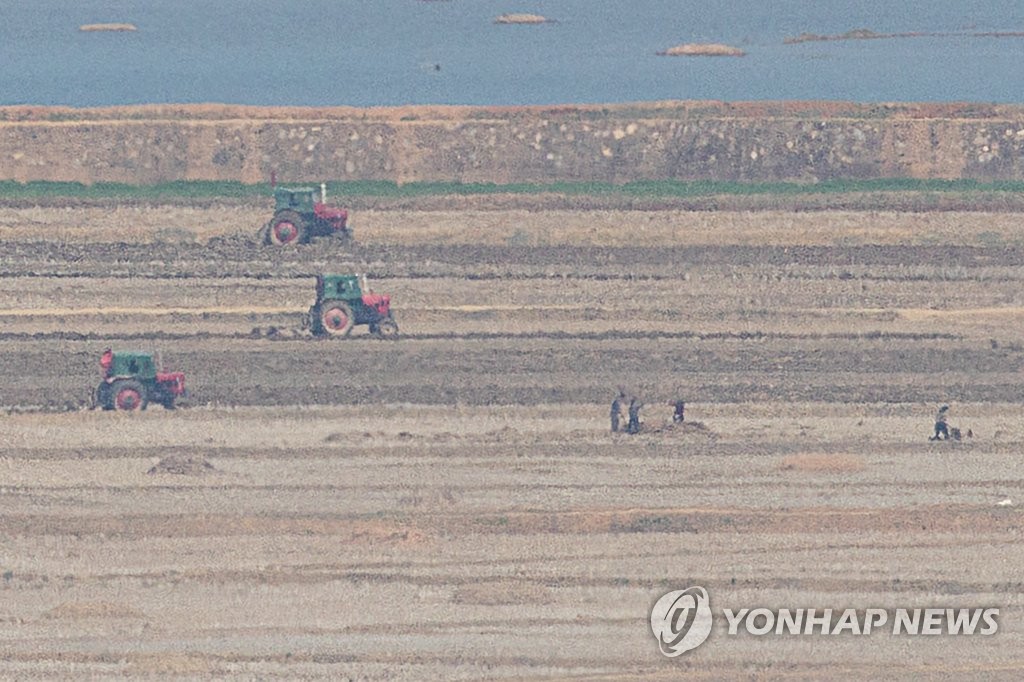 This photo taken from an observatory in the South Korean border city of Paju, some 30 kilometers north of Seoul, on April 15, 2022, shows North Korean farmers tilling a field with tractors in the North Korean town of Kaepung on the western front-line border with South Korea as the North marked the 110th anniversary of the birth of the country's late founder Kim Il-sung. (Yonhap)