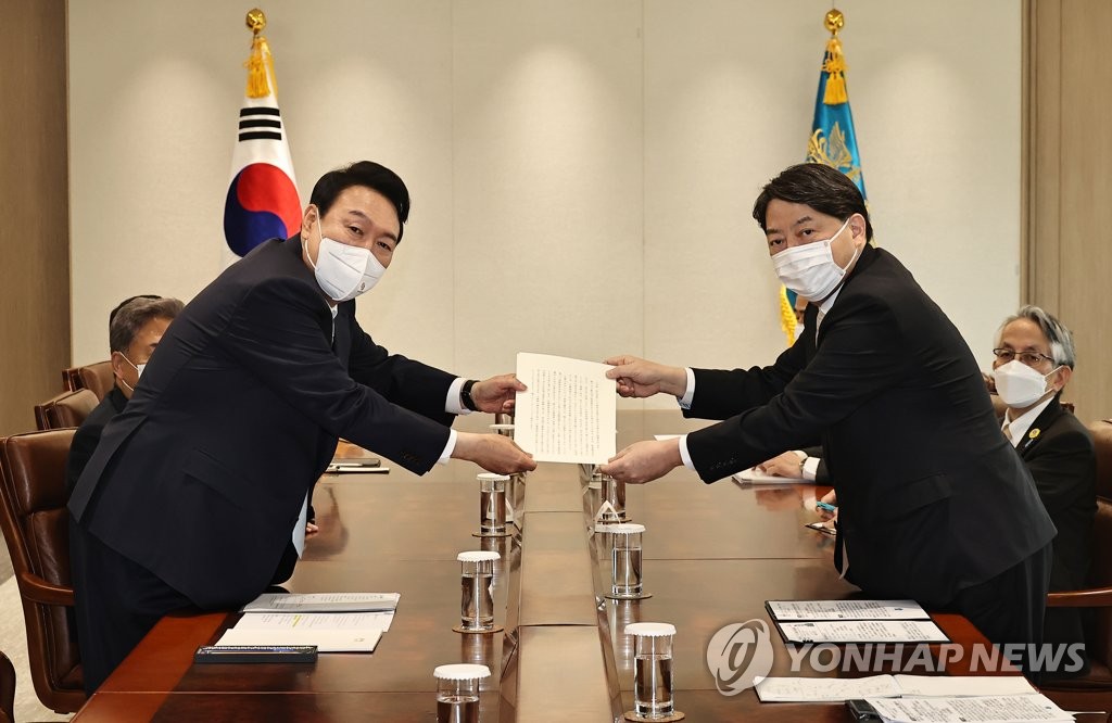 South Korean President Yoon Suk-yeol (L) poses for a photo while receiving Japanese Prime Minister Fumio Kishida's personal letter to him via Japanese Foreign Minister Yoshimasa Hayashi (R) at his office in Seoul on May 10, 2022. Hayashi attended Yoon's inaugural ceremony earlier in the day. (Yonhap)