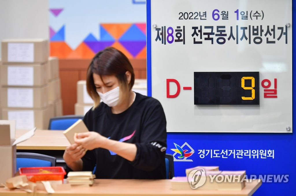 An official of a regional office of the National Election Commission in Suwon, about 45 kilometers south of Seoul, checks ballots on May 23, 2022, in front of a sign that reads there are nine days till the June 1 local elections. (Pool photo) (Yonhap)