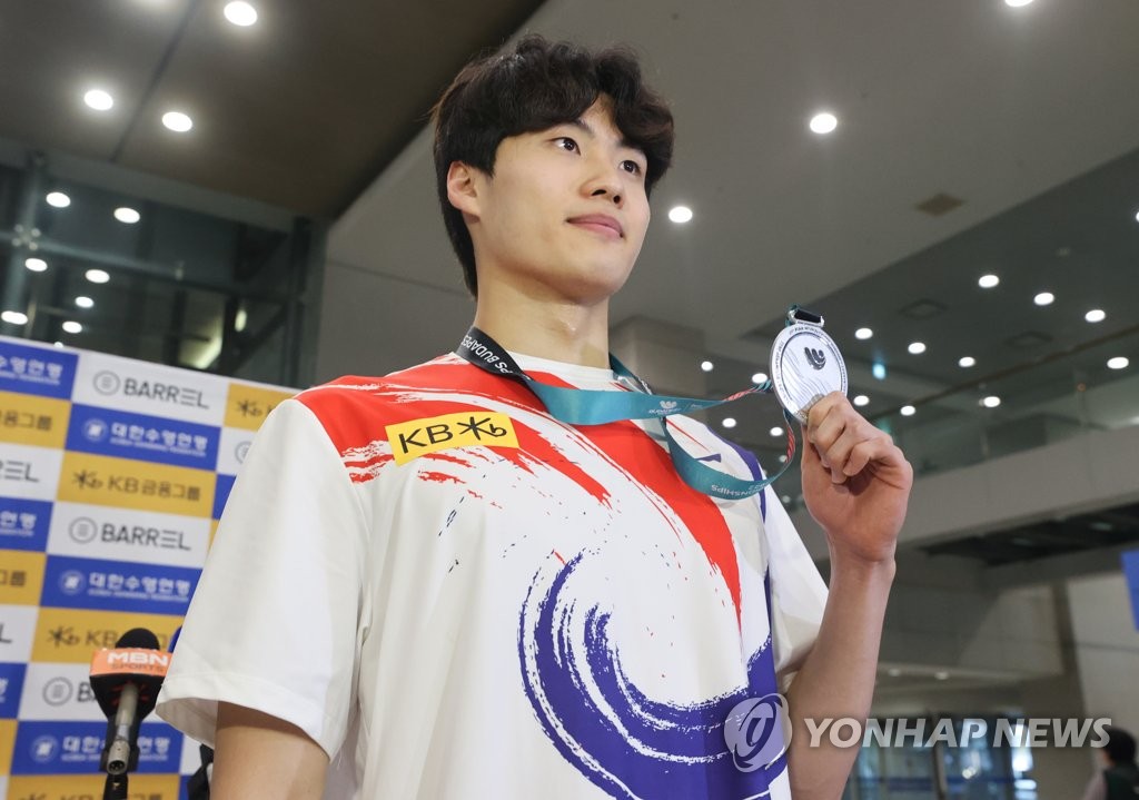 South Korean swimmer Hwang Sun-woo holds up his silver medal from the men's 200m freestyle at the FINA World Championships in Budapest, after arriving at Incheon International Airport in Incheon, just west of Seoul, on June 27, 2022. (Yonhap)