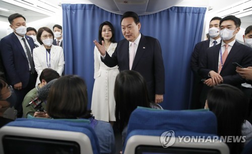 El presidente surcoreano, Yoon Suk-yeol (centro, frente), y la primera dama, Kim Keon-hee (centro, fondo), saludan al cuerpo de prensa, el 27 de junio de 2022 (hora local), dentro del avión presidencial con rumbo a Madrid, España.
