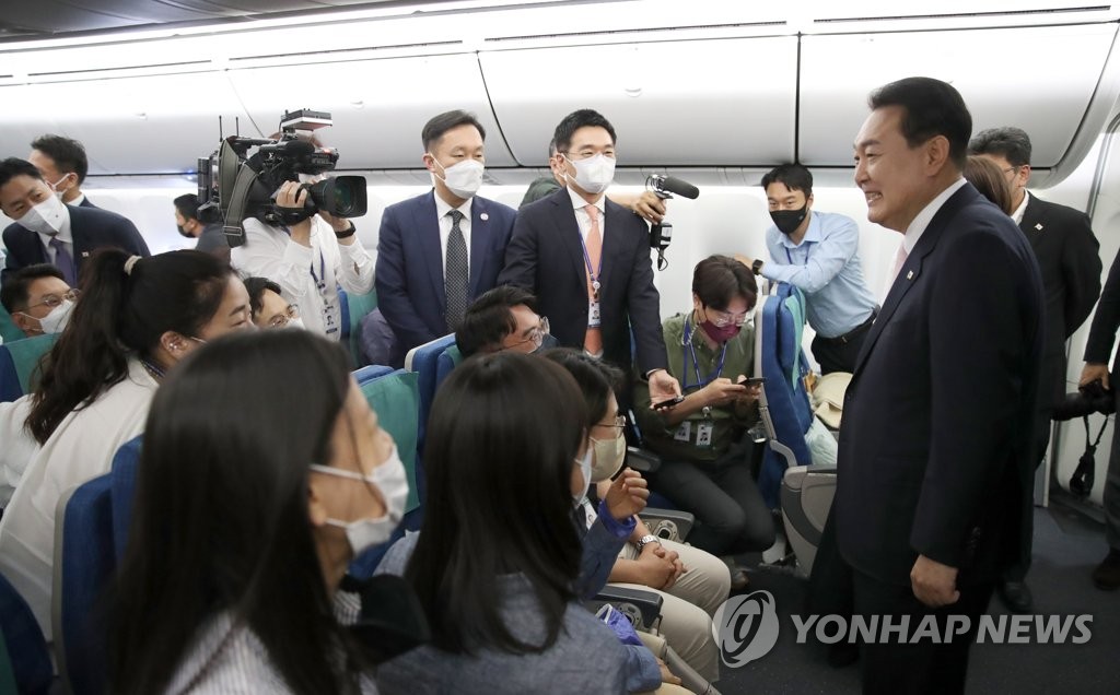 South Korean President Yoon Suk-yeol (R) greets reporters on the presidential plane on his way to Madrid on June 27, 2022, to attend the NATO summit on his first overseas trip as president. (Yonhap)