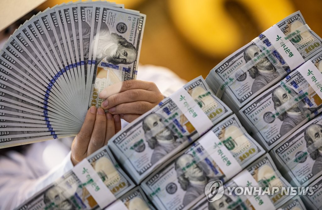 A clerk scrutinizes U.S. banknotes at the headquarters of Hana Bank in Seoul on Aug. 23, 2022, to determine whether any are counterfeit. (Yonhap)
