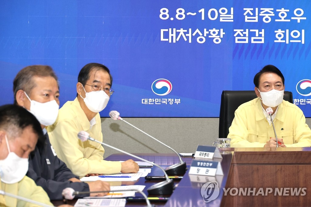 President Yoon Suk-yeol (R) presides over an emergency meeting at the government complex in Seoul on Aug. 10, 2022, to check countermeasures against record torrential rain in Seoul and surrounding areas. (Yonhap)