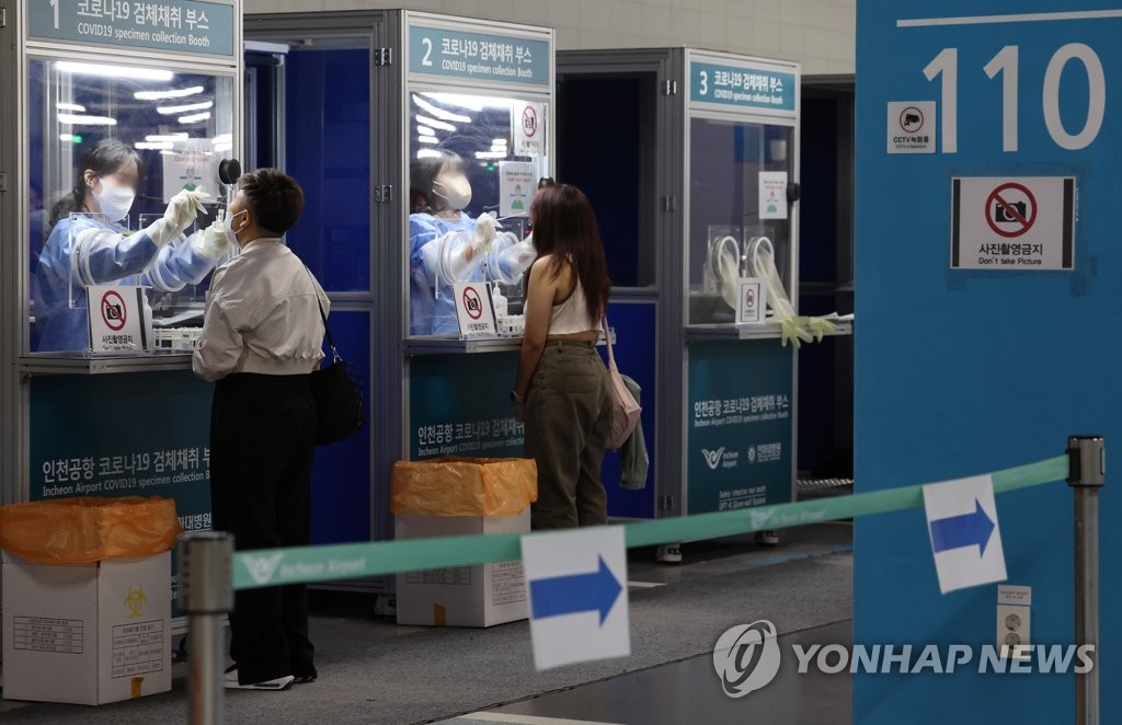 Medical workers take COVID-19 swab samples from foreign travelers at testing booth set up in a main passenger terminal of Incheon International Airport, west of Seoul, on Aug. 29, 2022. (Yonhap) 