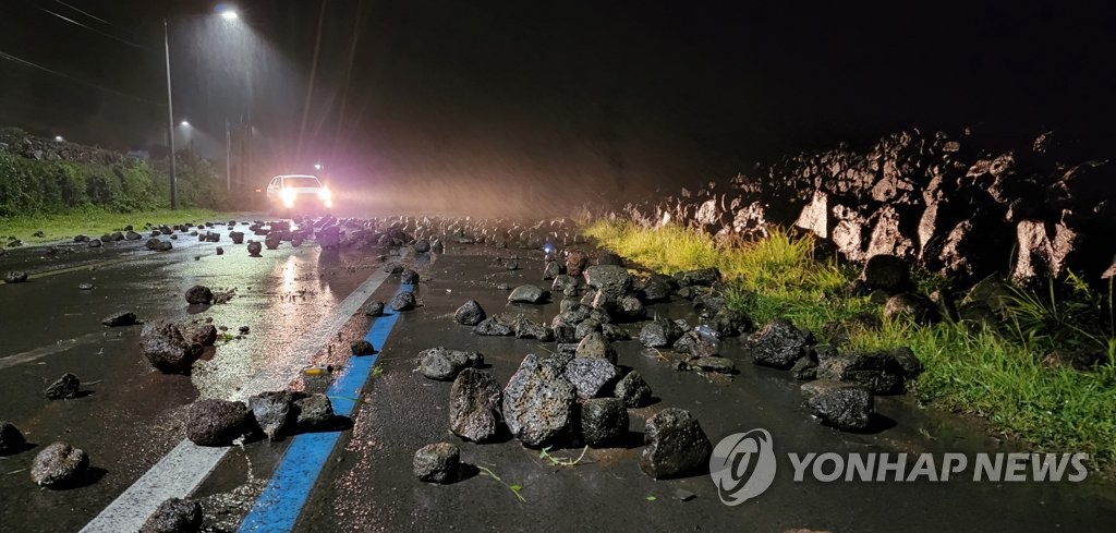 南部・済州島の西帰浦市の海岸道路に大きな石が散らばっている＝６日、済州（聯合ニュース）