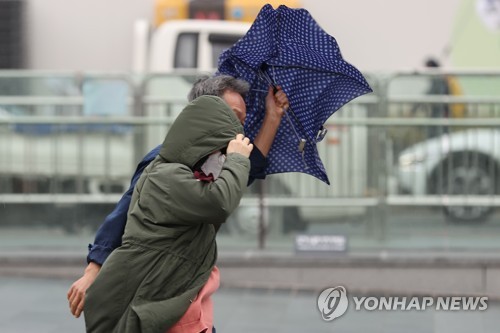 서울 종로구 광화문역 인근에서 시민들이 비바람에 날리는 우산을 붙잡고 있다. [연합뉴스 자료사진]