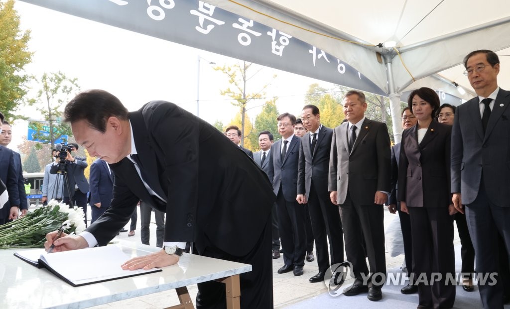 President Yoon Suk-yeol signs a condolence book at a mourning altar for victims of the Itaewon crowd crush near Noksapyeong Station in Seoul on Nov. 1, 2022. (Yonhap)