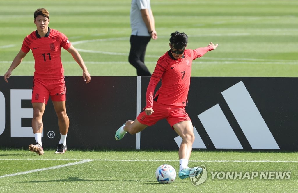 South Korean captain Son Heung-min (R) trains wearing a protective mask at Al Egla Training Facility in Doha on Nov. 16, 2022, in preparation for the FIFA World Cup. (Yonhap)