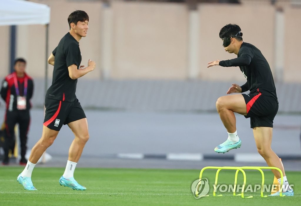 El capitán de la selección surcoreana, Son Heung-min (dcha.), entrena utilizando una máscara negra sobre su rostro lastimado, junto con su compañero de equipo Hwang Ui-jo, el 22 de noviembre de 2022, en la Instalación de Entrenamiento Al Egla en Doha, Catar.