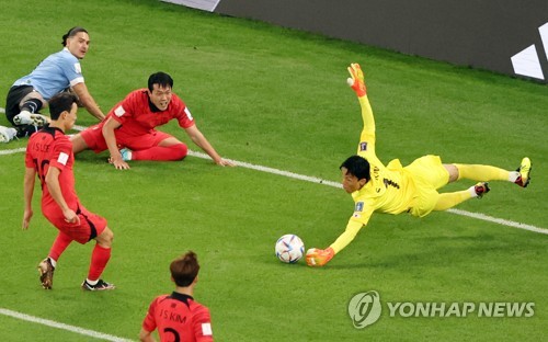 South Korean goalkeeper Kim Seung-gyu (R) stops a cross by Uruguay during the countries' Group H match at the FIFA World Cup at Education City Stadium in Al Rayyan, west of Doha, on Nov. 24, 2022. (Yonhap)