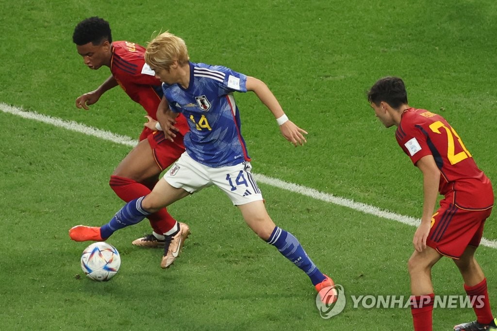 Junya Ito of Japan (C) and Rodri of Spain (L) battle for the ball during the countries' Group E match at Khalifa International Stadium in Al Rayyan, west of Doha, on Dec. 1, 2022. (Yonhap)