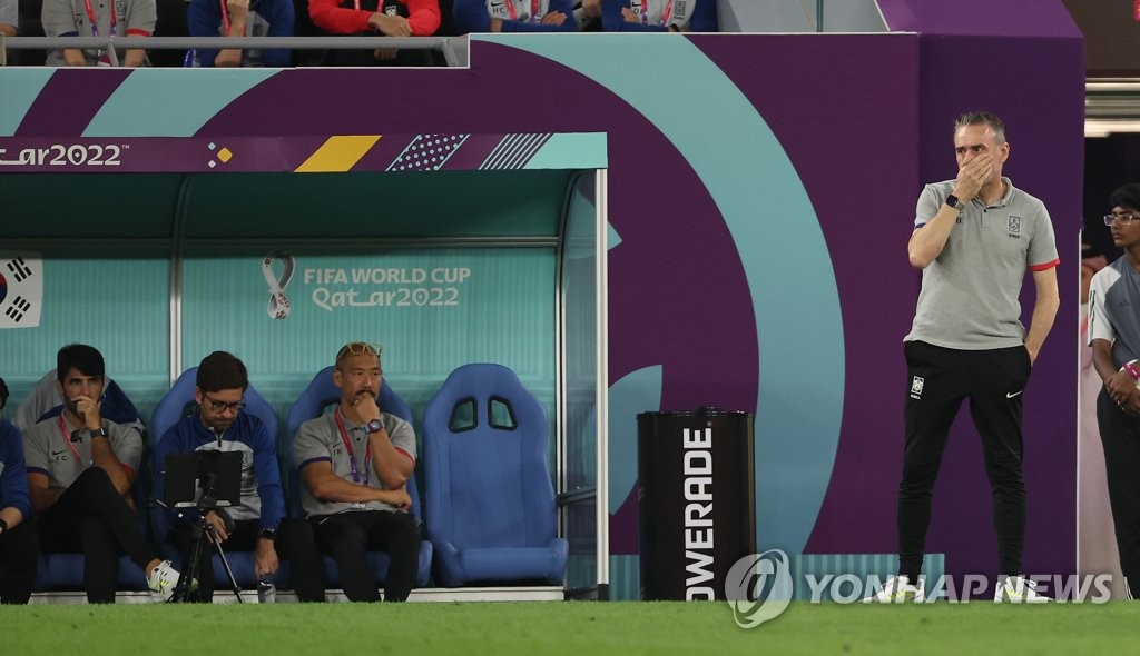 South Korea head coach Paulo Bento (R) and his staff watch their team in action against Brazil during the countries' round of 16 match at the FIFA World Cup at Stadium 974 in Doha on Dec. 5, 2022. (Yonhap)