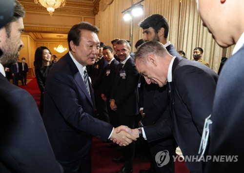 President Yoon Suk-yeol (L) shakes hands with Paulo Bento, head coach of South Korea's national football team, before a dinner he hosted for the national football team at the former presidential compound of Cheong Wa Dae in Seoul on Dec. 8, 2022. (Yonhap)