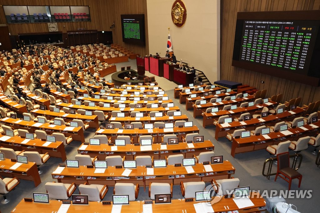 Los legisladores de los partidos de oposición votan para aprobar un informe sobre la investigación parlamentaria de la tragedia de Itaewon, el 30 de enero de 2023, en una sesión plenaria, en la Asamblea Nacional, en el oeste de Seúl. 