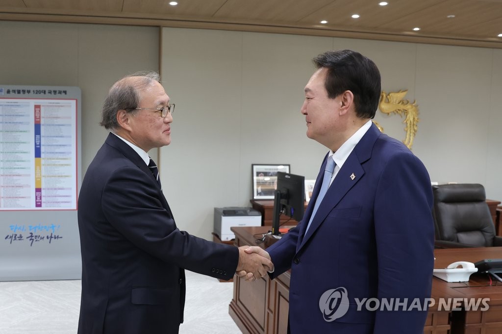 President Yoon Suk Yeol (R) shakes hands with Takeo Akiba, secretary general of Japan's National Security Secretariat, at his office in Seoul on May 3, 2023, in this photo provided by the presidential office. (PHOTO NOT FOR SALE) (Yonhap)
