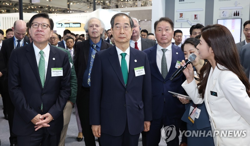 Prime Minister Han Duck-soo (C) tours an exhibition hall with Busan Mayor Park Heung-joon (L) and SK Group Chairman Chey Tae-won (4th from L) at the Busan Exhibition & Convention Center (BEXCO) in the southeastern port city, where the World Climate Industry Expo is taking place from May 25-27, 2023. (Yonhap) 