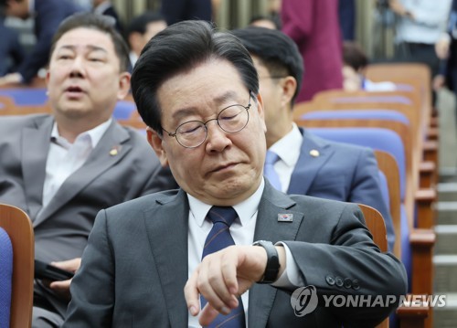 Main opposition Democratic Party leader Lee Jae-myung checks the time on his watch at the National Assembly in Seoul on May 25, 2023. (Yonhap)