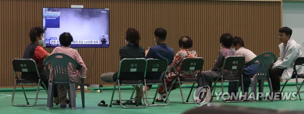 People watch the weather forecast at a temporary shelter in hard-hit North Gyeongsang Province on July 18, 2023. (Yonhap)